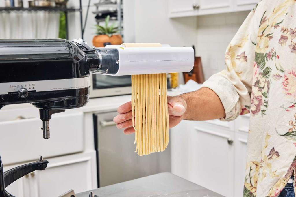 Eco-friendly kitchen setup featuring a Made in Italy electric pasta maker with dough sheets and fresh herbs nearby.
