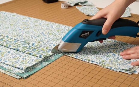 Person using electric sewing scissors to cut layered fabric smoothly on a table