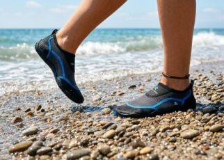 : A person walking on a rocky beach wearing comfortable water socks.
