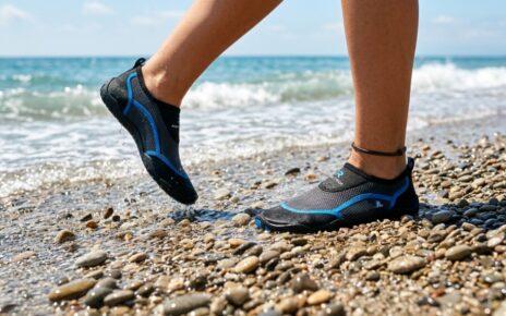 : A person walking on a rocky beach wearing comfortable water socks.