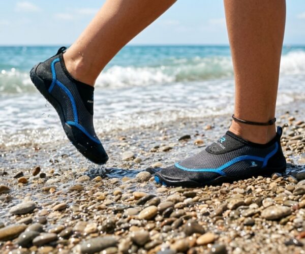 : A person walking on a rocky beach wearing comfortable water socks.