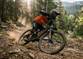 Mountain biker cornering on a rugged singletrack trail with elbows out for balance.