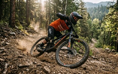 Mountain biker cornering on a rugged singletrack trail with elbows out for balance.