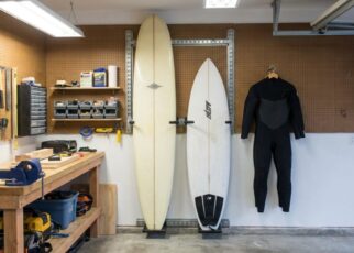 Surfboard mounted horizontally on a small apartment living room wall above a modern couch.