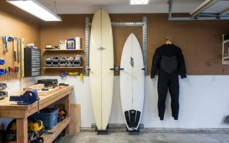 Surfboard mounted horizontally on a small apartment living room wall above a modern couch.