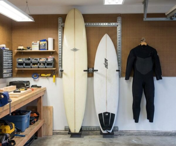 Surfboard mounted horizontally on a small apartment living room wall above a modern couch.