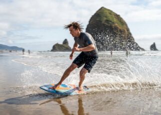 A high-end skimboard resting on the wet sand of a misty Oregon beach.