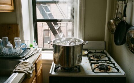 Stainless steel pot boiling baby bottles on a stove burner.
